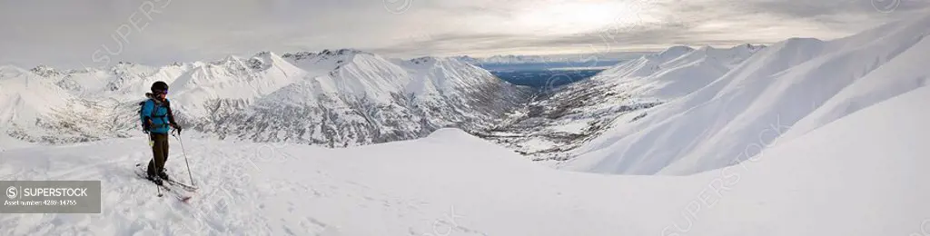 A backcountry skier takes a moment to enjoy the view from the top of Hatcher Pass, Alaska
