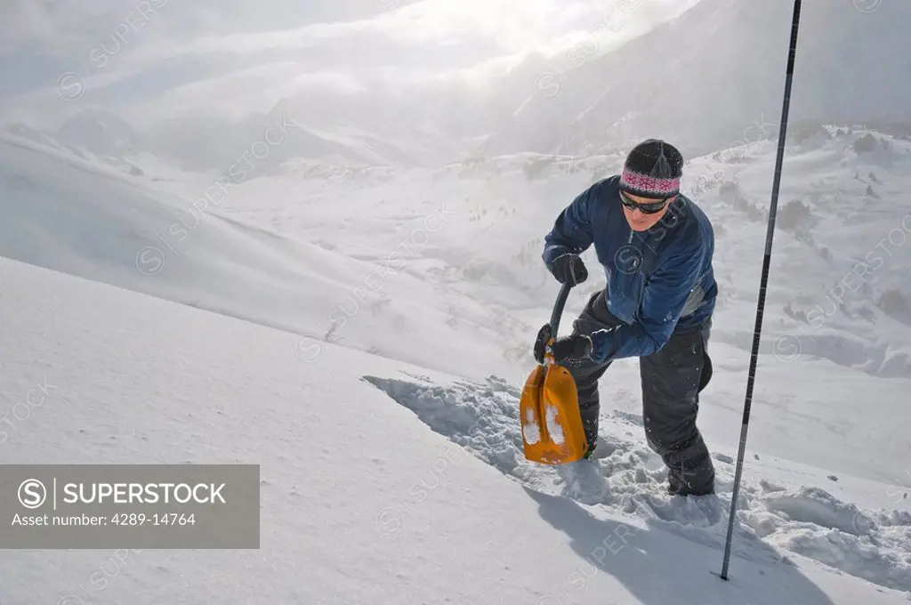 A backcountry skier digs a snow pit to test the conditions of the snow pack, Turnagain Pass, Alaska