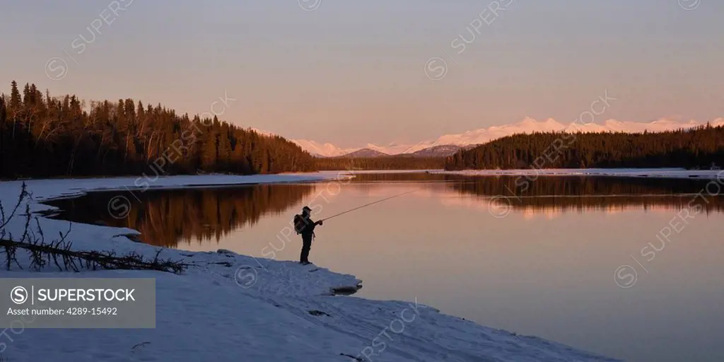 Lone fisherman fishing the Kenai River in Winter at Sunset