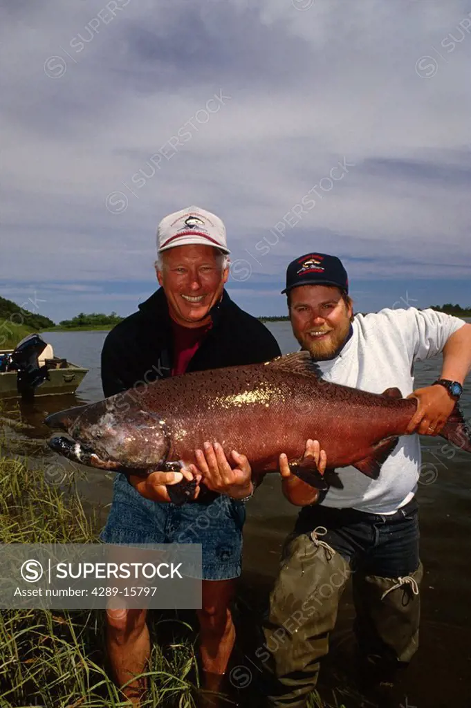 Fisherman & guide holding large king salmon near shoreline Nushagak River Southwest AK Summer