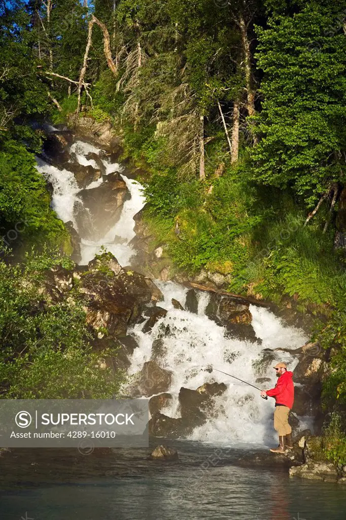 Fisherman spin fishing for salmon at the base of Fisher Falls at Big River Lakes in Redoubt Bay State Critical Habitat Area, Southcentral Alaska