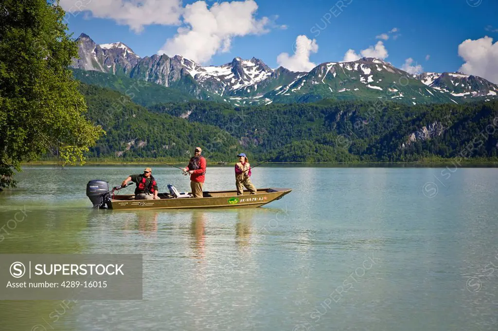 Man and Woman spin fish while standing in a boat in Big River Lakes in the Redoubt Bay State Critical Habitat Area in Southcentral Alaska during Summe...