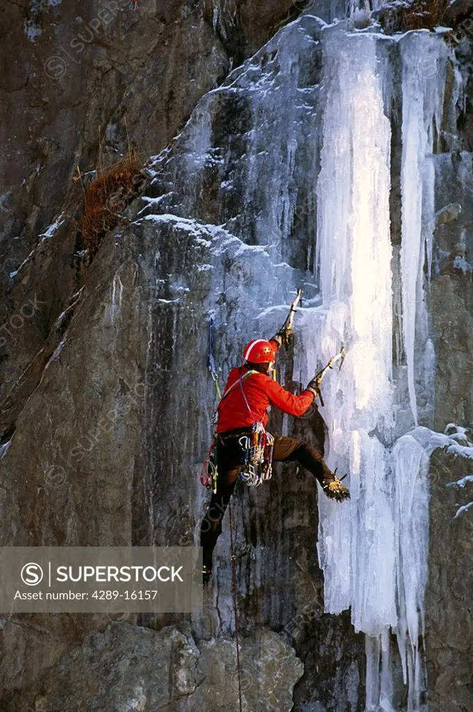 Male ice climber using ice picks to climb frozen waterfall on Turnagain Arm Chugach Mtns SC Alaska