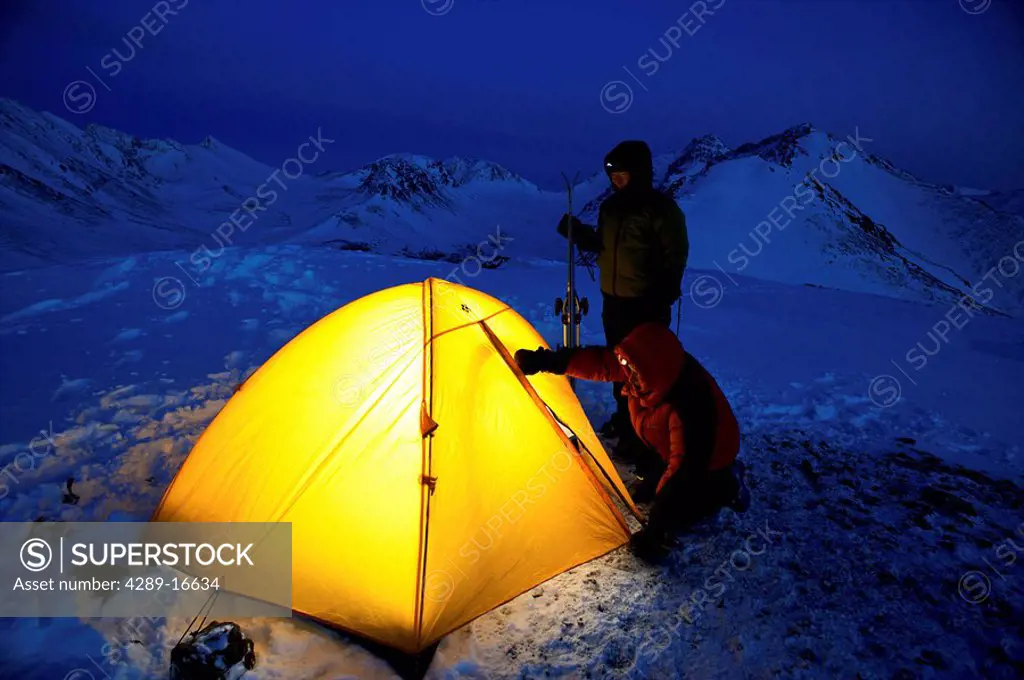 Climbers enter a lit tent to spend the night at camp in the Chugach Mountains near Anchorage, Chugach State Park, Southcentral Alaska,/nSpring