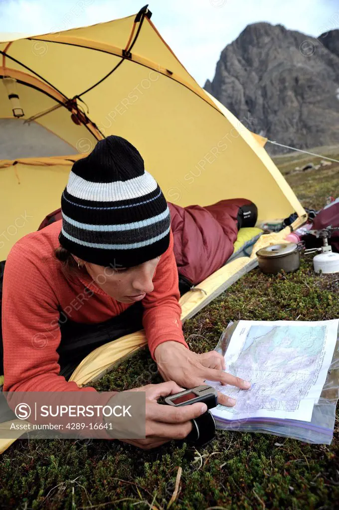 Woman in a tent consults a GPS and map while camping at Rabbit Lake, Chugach State Park, Southcentral Alaska, Autumn