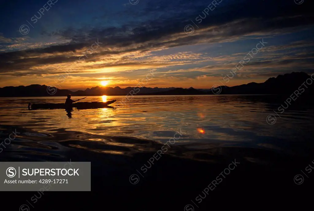 Woman kayaking in Berners Bay against setting sun Southeast Alaska Summer Backlit Silhouette