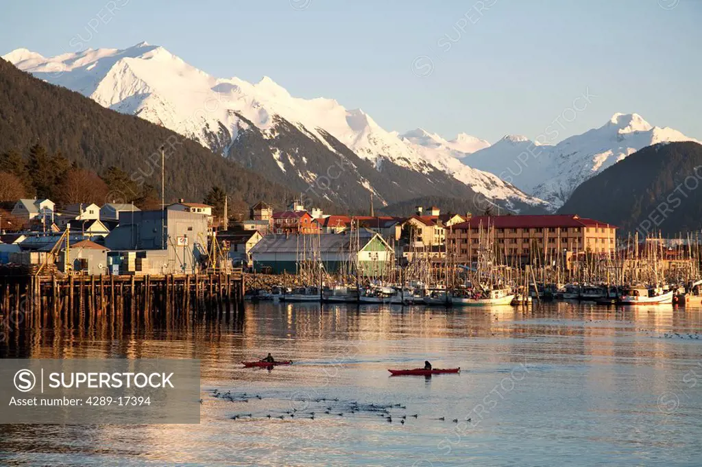 Kayakers in Sitka Sound at sunset between Japonski & Baranof Islands with Sitka in background, Southeast, Alaska