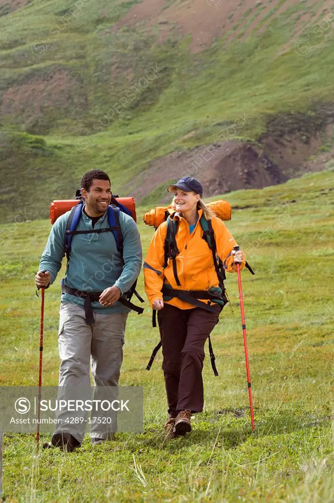 Afro_American man & caucasian woman hiking together on tundra near Eielson Visitor Center Denali National Park Alaska