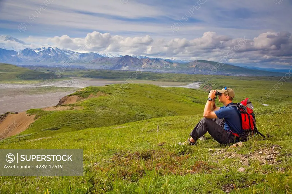 Male hiker views Throughfare River at Grassy Pass near Eielson visitor center Denali NP Alaska