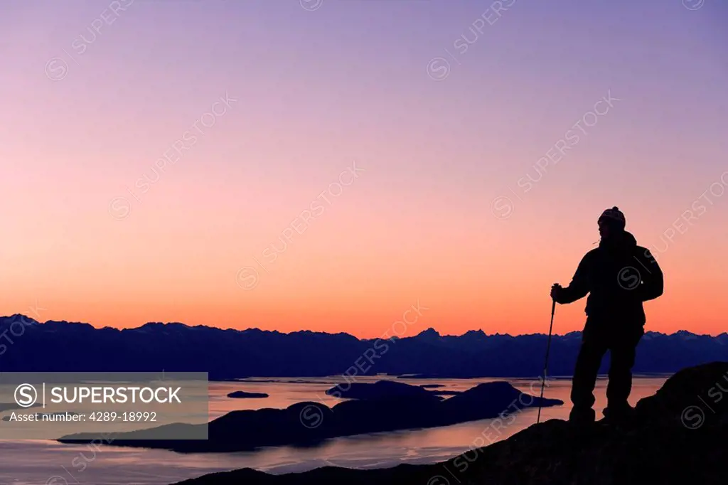 Male Hiker standing on ridge overlooking Lynn Canal & Berner´s Bay near Juneau Alaska at sunset