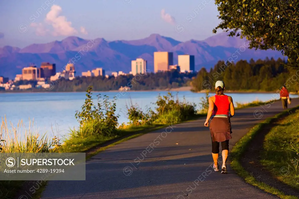 People jogging, walking and biking on the Tony Knowles Coastal Trail with Downtown Anchorage skyline in the distance, Anchorage, Southcentral Alaska, ...