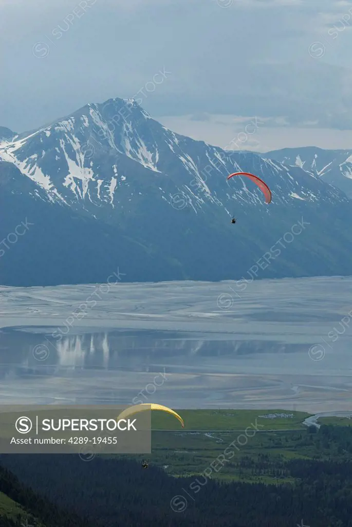 Two paragliders soar above the Girdwood Valley with Turnagain Arm in the background, Southcentral Alaska