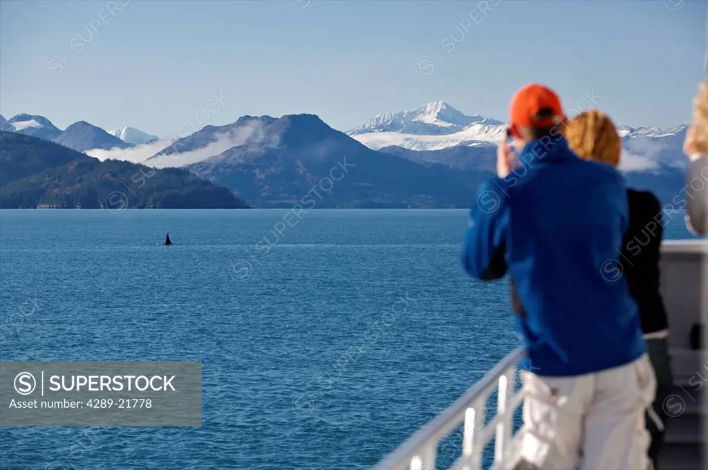 Tourists watch an Orca whale from their tour boat in Prince William Sound, Alaska