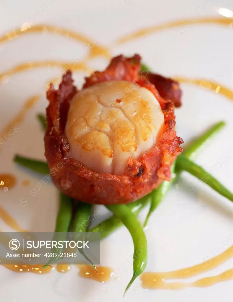 Close up of a gourmet appetizer of seared jumbo weathervane scallop wrapped with salumi chorizo