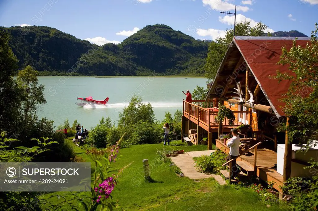 Guests of Redoubt Bay Lodge relax on the deck and in the front yard of the main lodge and watch a Rust´s Flying Service plane take off from Big River ...