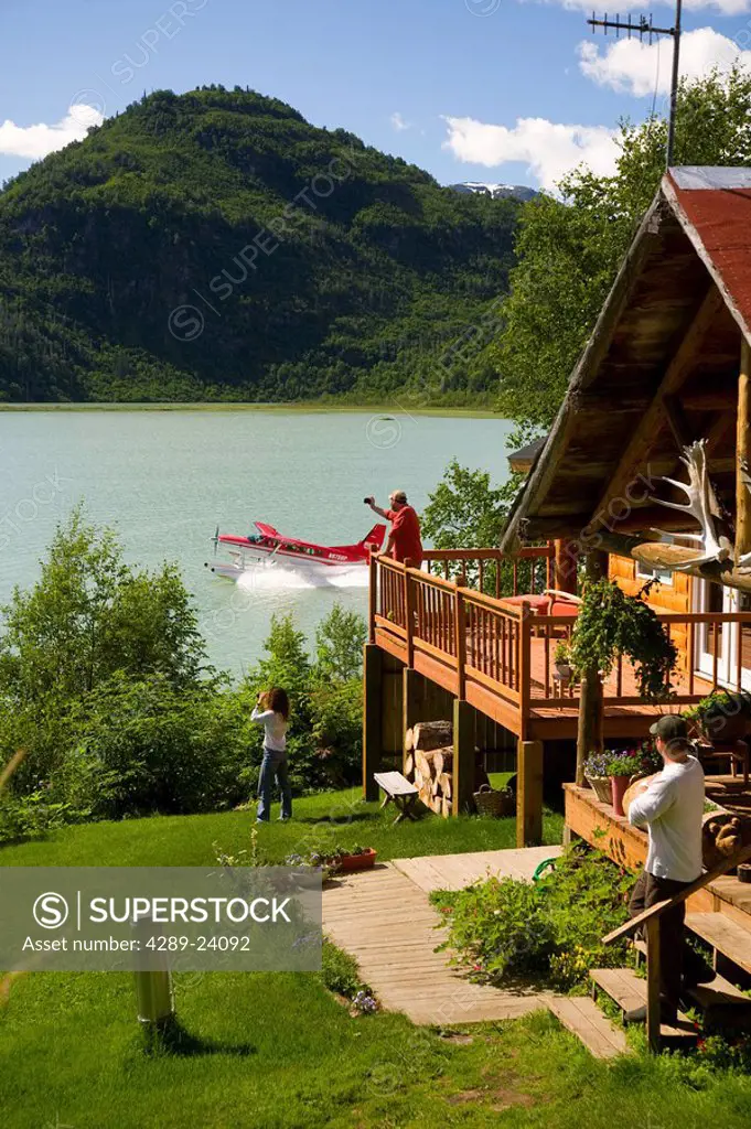 Guests of Redoubt Bay Lodge relax on the deck and in the front yard of the main lodge and watch a Rust´s Flying Service plane take off from Big River ...