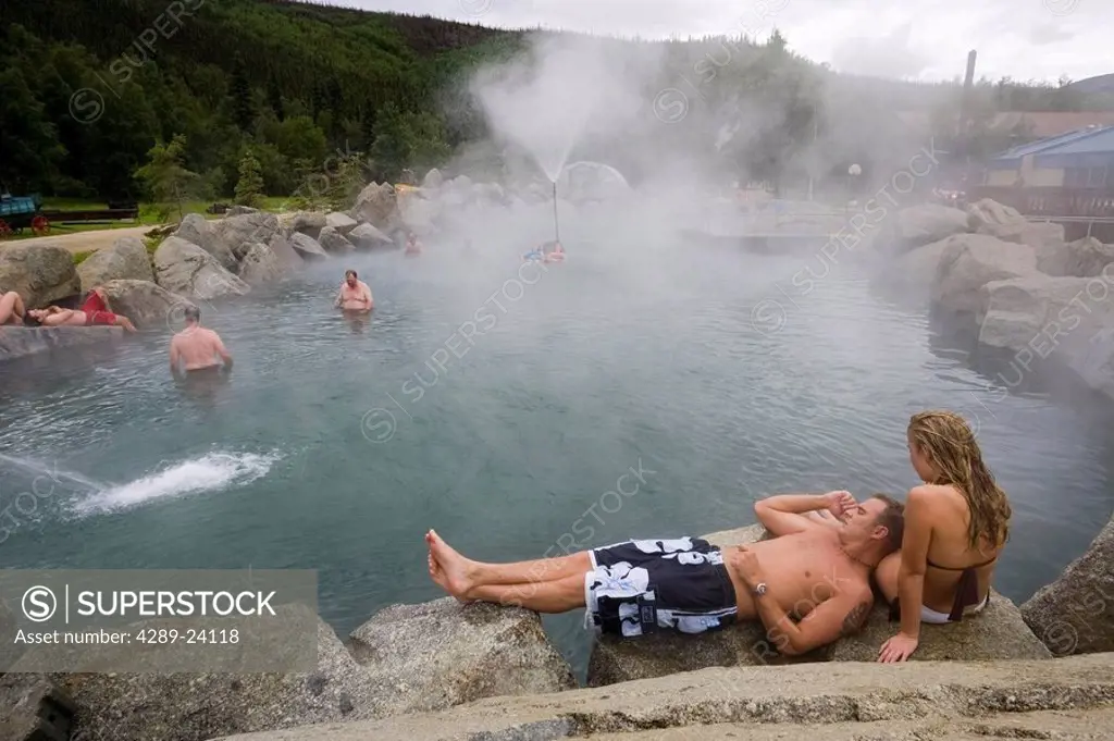Couple relax by Chena Hot Springs pool at Chena Hot Springs Resort near Fairbanks Alaska Interior summer