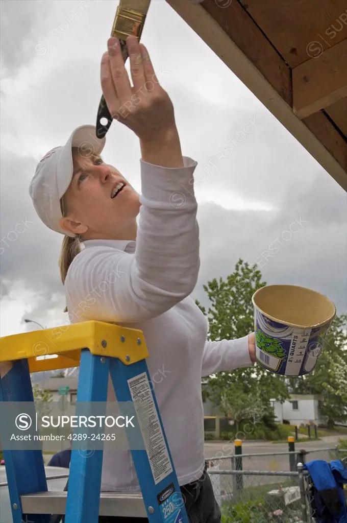 Rotary Club participant helps paint a house in the Anchorage Neighborhood Housing Paint the Town project, Alaska