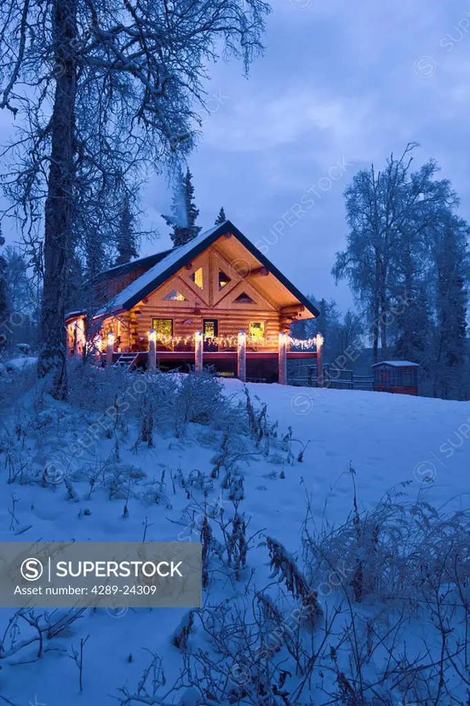 Log Cabin in the woods decorated with Christmas lights at twilight near Fairbanks, Alaska during Winter