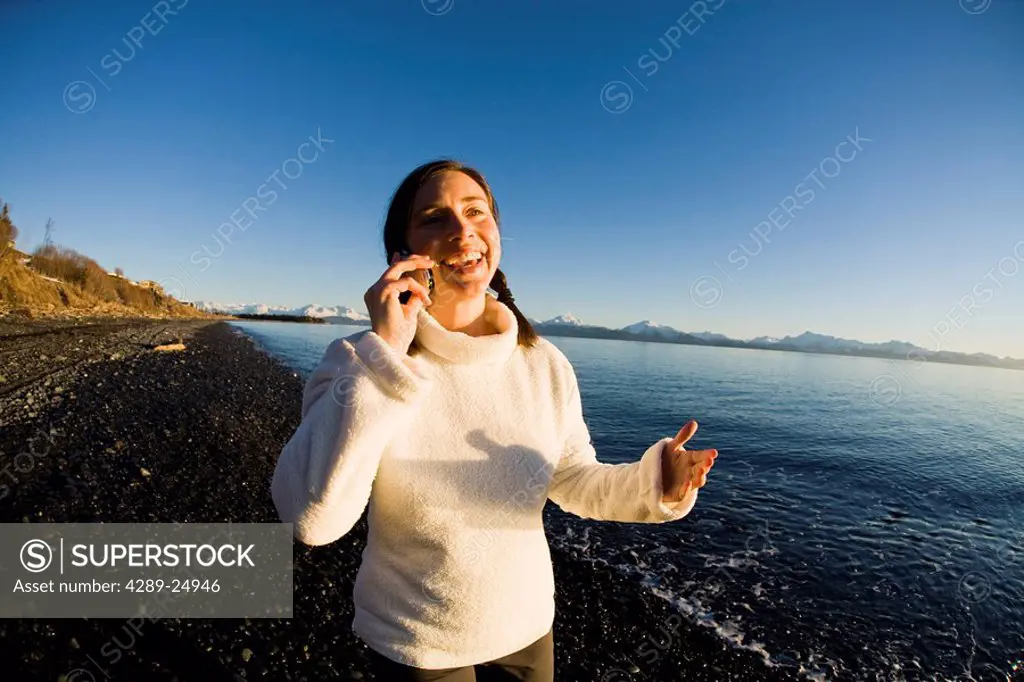 Woman talks on a cell phone at Bishops Beach at Kachemak Bay in Homer, Alaska