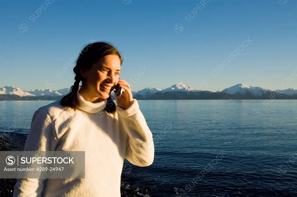 Woman talks on a cell phone at Bishops Beach at Kachemak Bay in Homer, Alaska