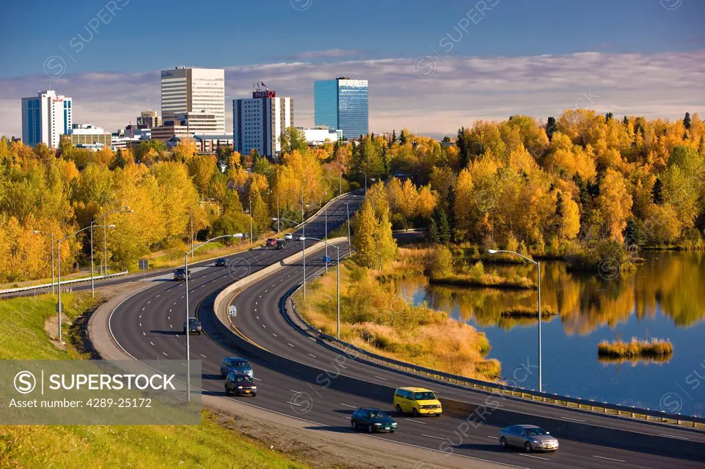 Scenic view of Minnesota Blvd. traffic along Westchester Lagoon on a sunny day with downtown Anchorage in the distance, Southcentral Alaska, Fall