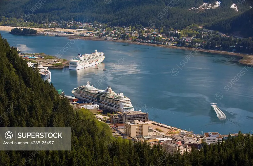 A floatplane takes off in Gastineau Channel with a view of three cruise ships docked in downtown Juneau, Southeast Alaska