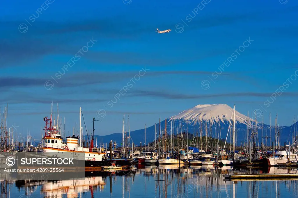 An Alaska Airlines jet takes off over Mt. Edgecumbe and the small boat harbor in Sitka, Alaska
