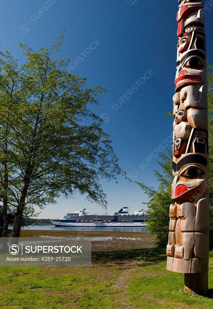 Totem pole with the coastline and a cruiseship in the background, Sitka National Historic Park, Alaska