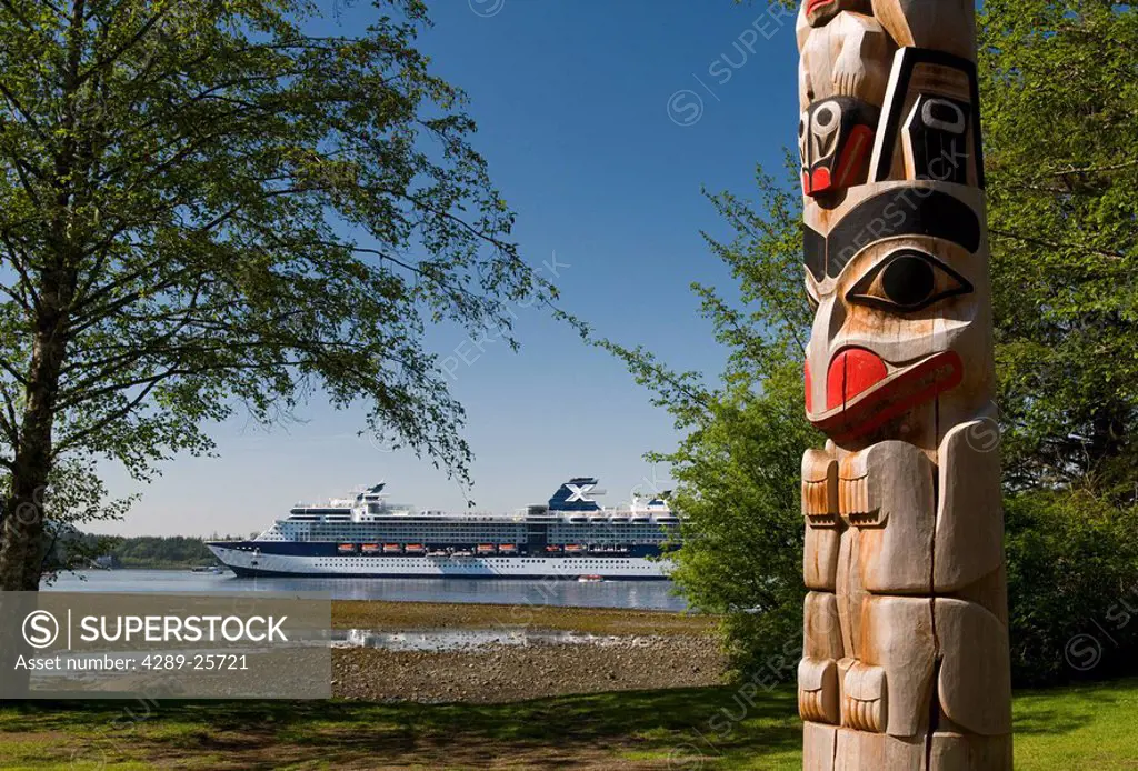 Totem pole with the coastline and a cruiseship in the background, Sitka National Historic Park, Alaska