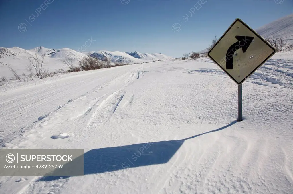 Sign marking a right_hand corner is nearly buried in deep snow on the Denali Highway during Winter in Alaska