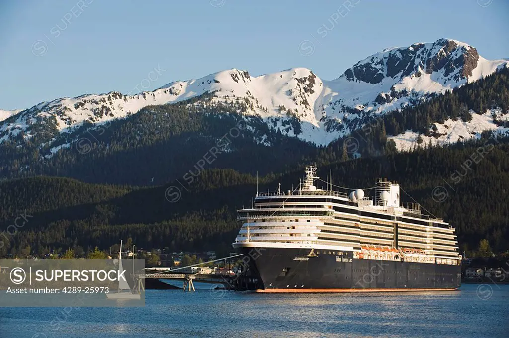 A sailboat passes in front of the docked Holland America Line cruise ship/nZuiderdam in Gastineau Channel, Juneau, Southeast Alaska
