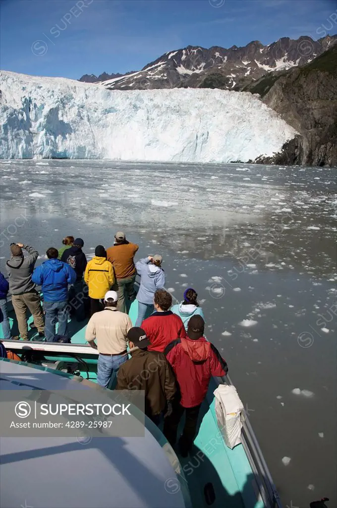 Tourists view glacier from the bow of a Kenai Fjords tour of Resurrection Bay, Seward, Alaska