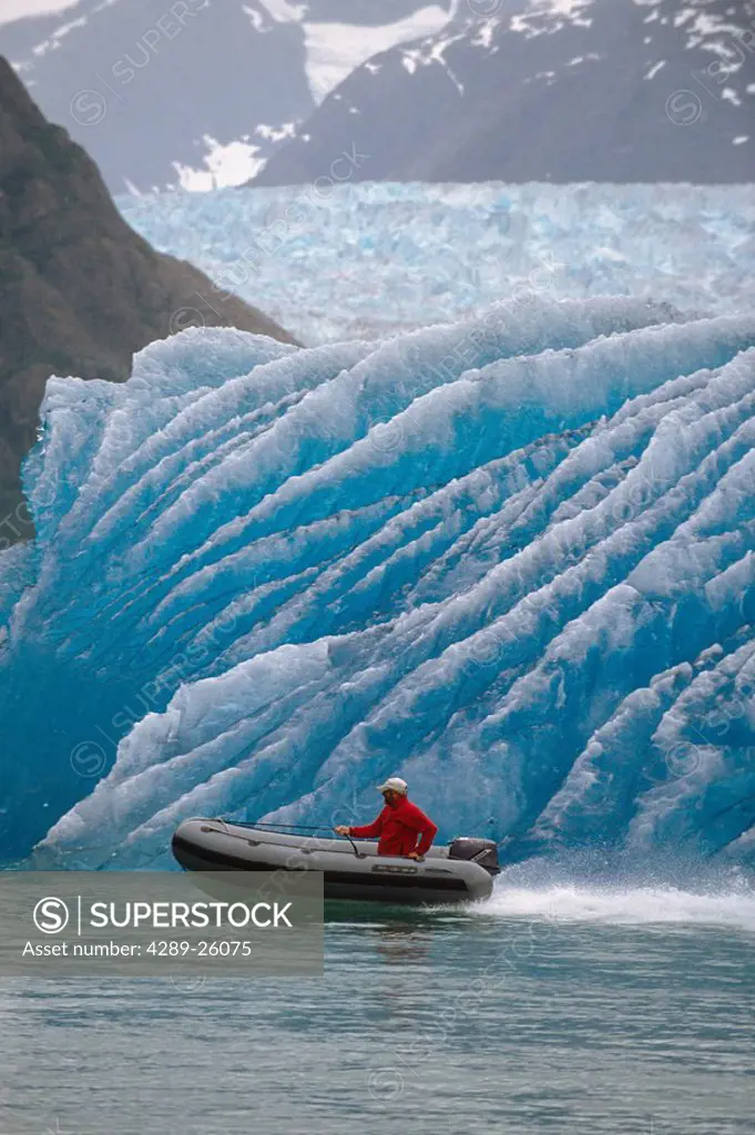 Man Motoring in Zodiac Across Face of Iceberg AK SE Summer