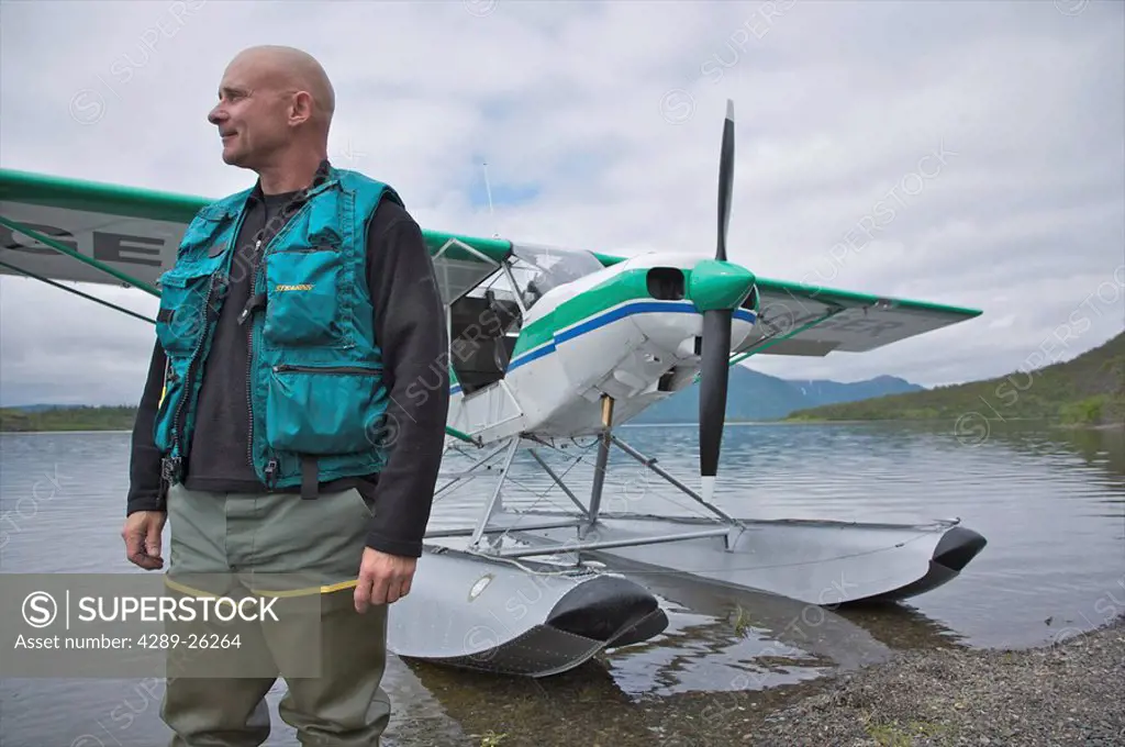Man stands with his Super Cub float plane on Lake Aleknagik, Wood Tikchik State Park, Western Alaska, Summer