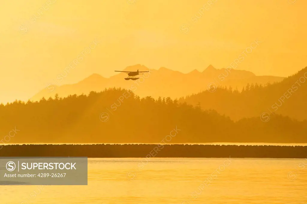 A silhouette of a float plane in flight at sunset near Sitka, Alaska
