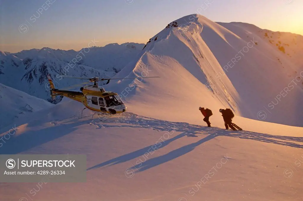 People hike to helicopter atop snow covered ridge @ sunrise Chugach Mtns Southcentral Alaska Winter