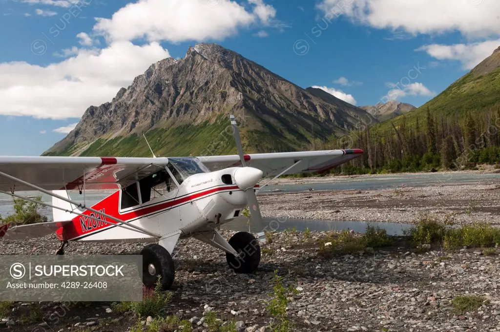 An Aviat Aircraft Husky A_1B rests on a gravel bar along the North Fork of the Koyukuk River with Frigid Crags looming in the background, Gates of the...