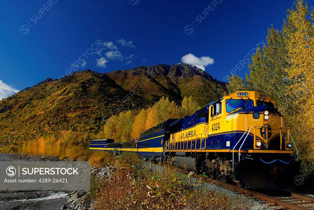 An Alaska Railroad passenger train runs along Turnagain Arm during a sunny Autumn day in Southcentral Alaska