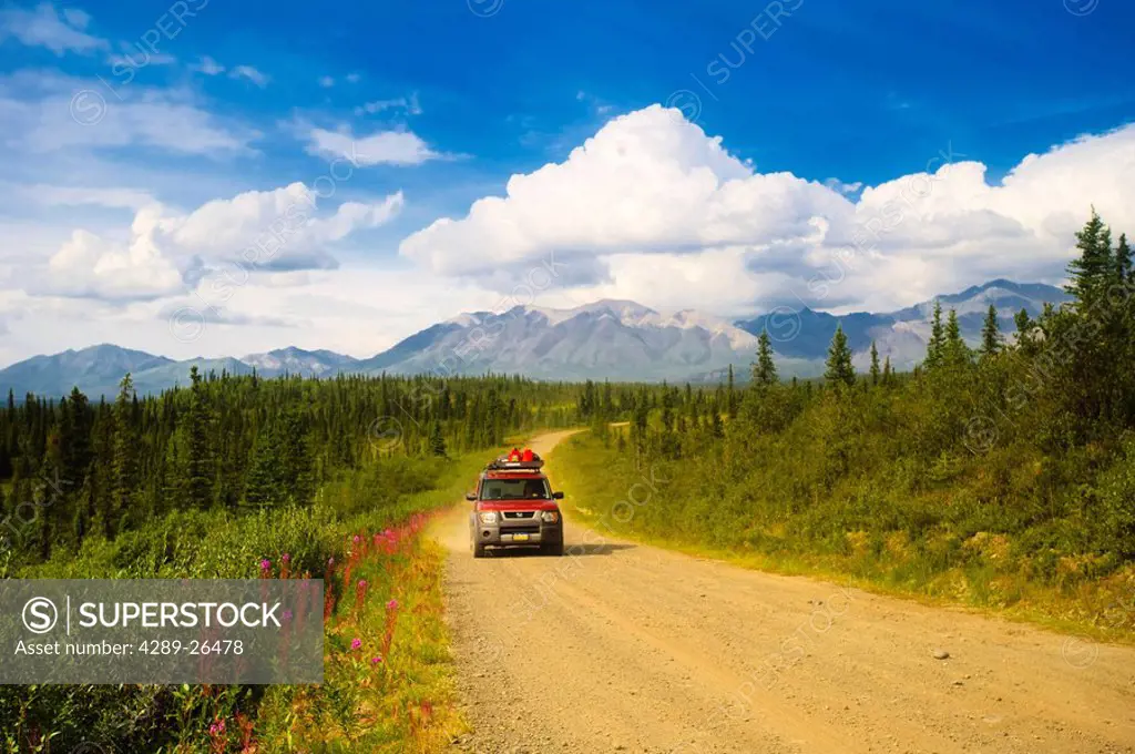 Car travelling on Nabesna Road in Wrangell Saint Elias National Park with the Mentasta Mountains in the background, Southcentral Alaska, Summer