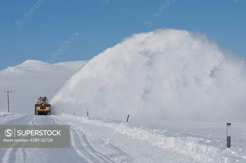 Snow plow removes snow from road near Nome, Alaska during Winter