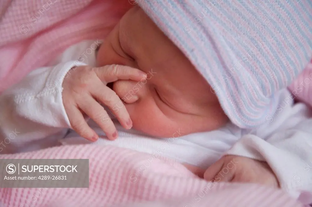 Close up of a newborn baby girl sucking on her thumb