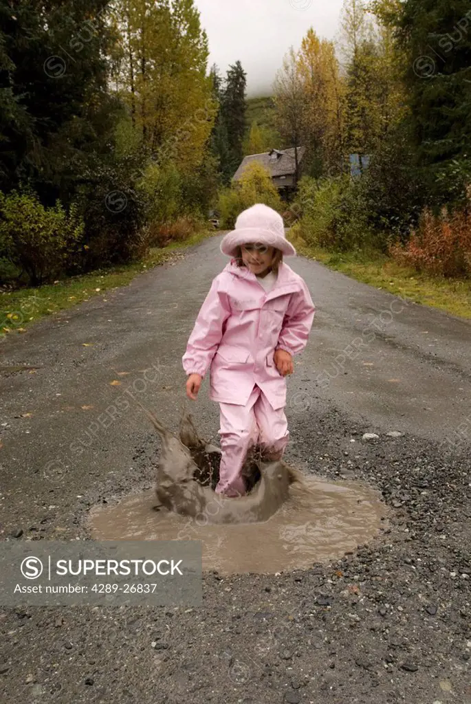 Young girl stepping in a mud puddle on a rainy Autumn day in Southcentral Alaska
