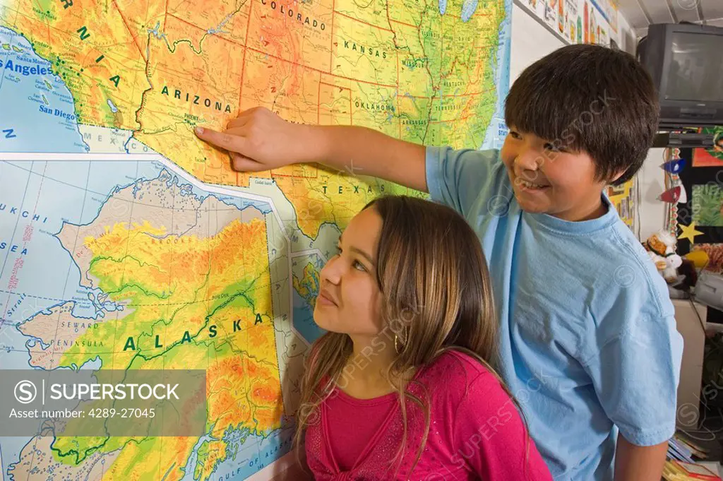 Alaskan native children in classroom reading map together inside Alaska Aleut