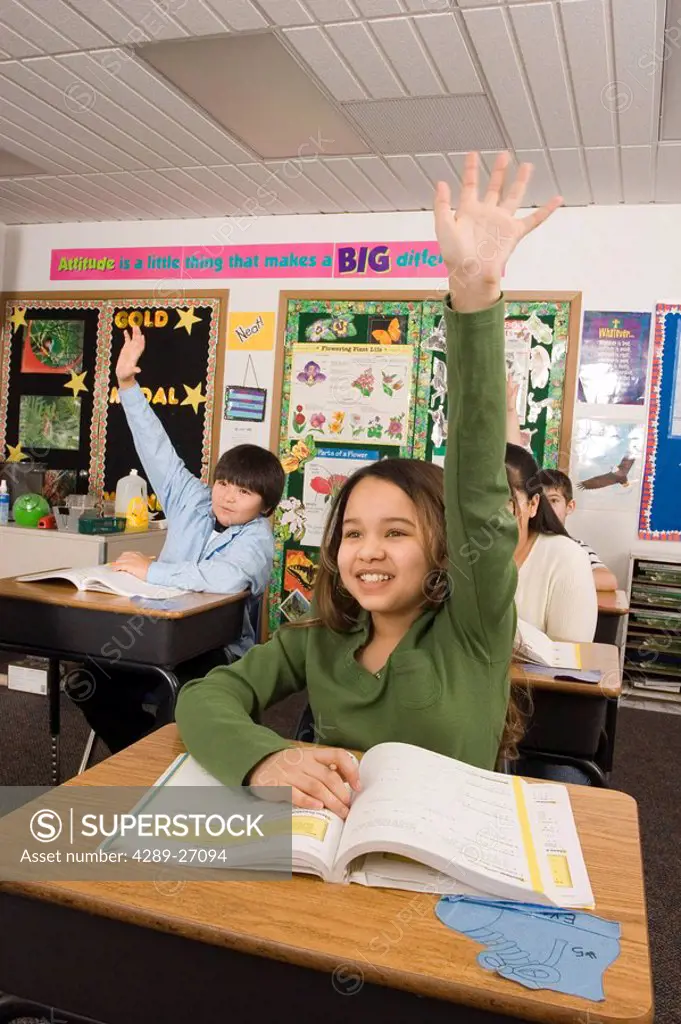 Alaskan native girl in classroom setting raising hand in participation inside Alaska