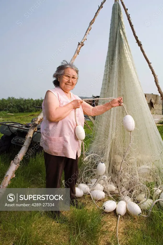 Elder native Yupik woman stands next to drift net she made for daughter Tuluksak Western Alaska