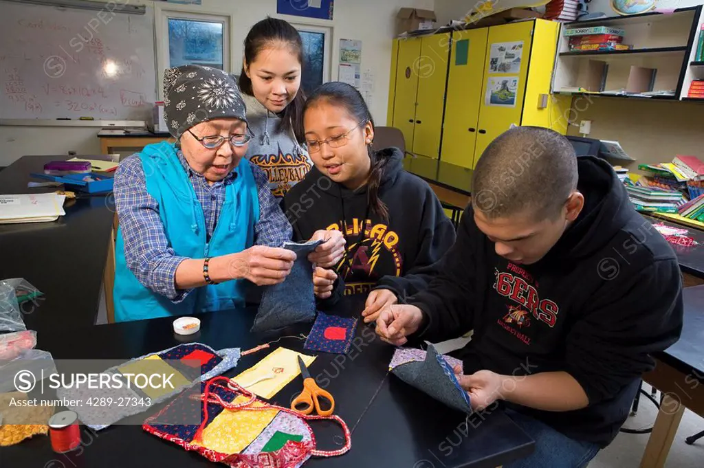 Elder native Yupik woman teaches youth to do bead work @ Akiak High School inside Western Alaska