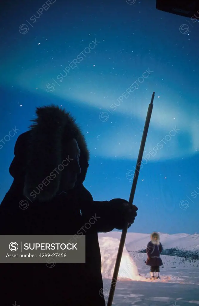 Eskimo man viewing Northern Lights over igloo Alaska composite winter scenic