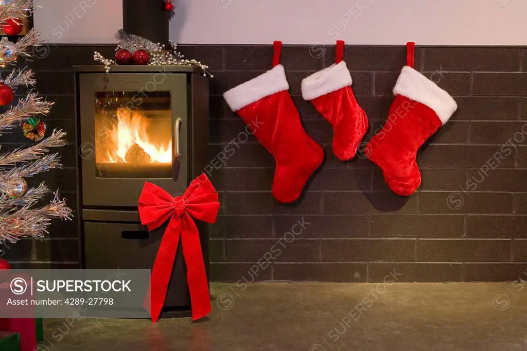 Christmas decor of stockings fireplace bow and tinsel tree in modern living room winter Alaska