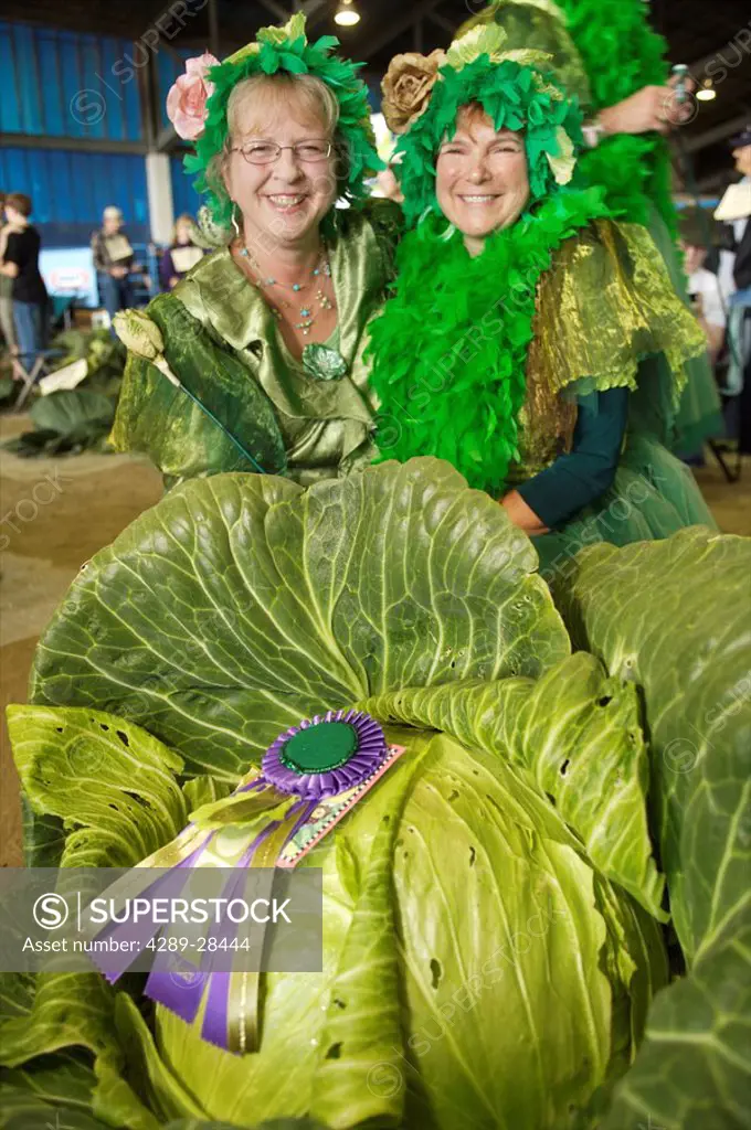 Two women in costume pose with the champion Giant Cabbage at the Alaska State Fair in Palmer, Alaska